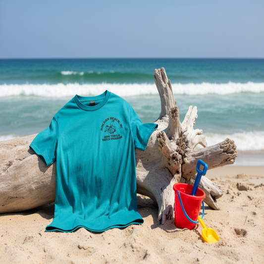 T-shirt draped over driftwood with sand toys
